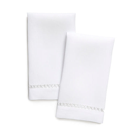 Two folded white napkins with delicate silver embroidered borders, arranged on a seamless white background.